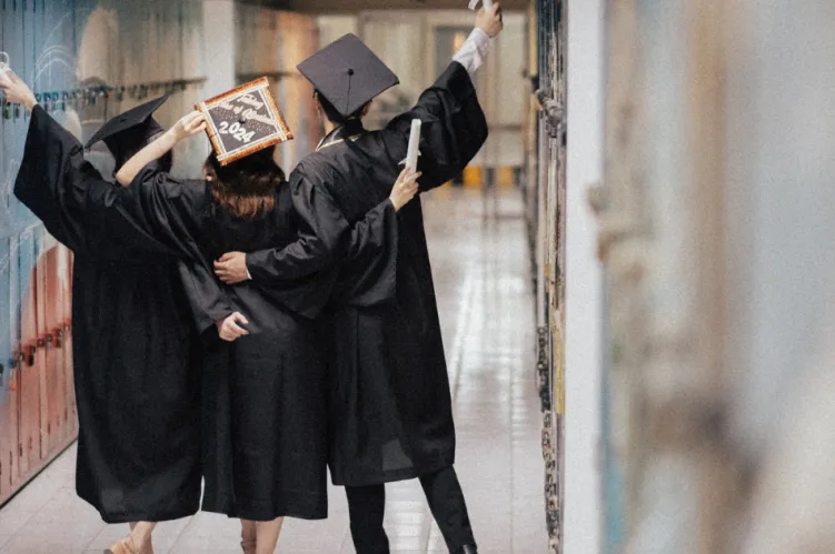 studenci w kitlach z podniesionymi w rękoma w geście radości 