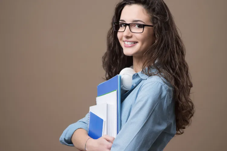 uśmiechnięta kobieta trzymająca podręczniki w ręku